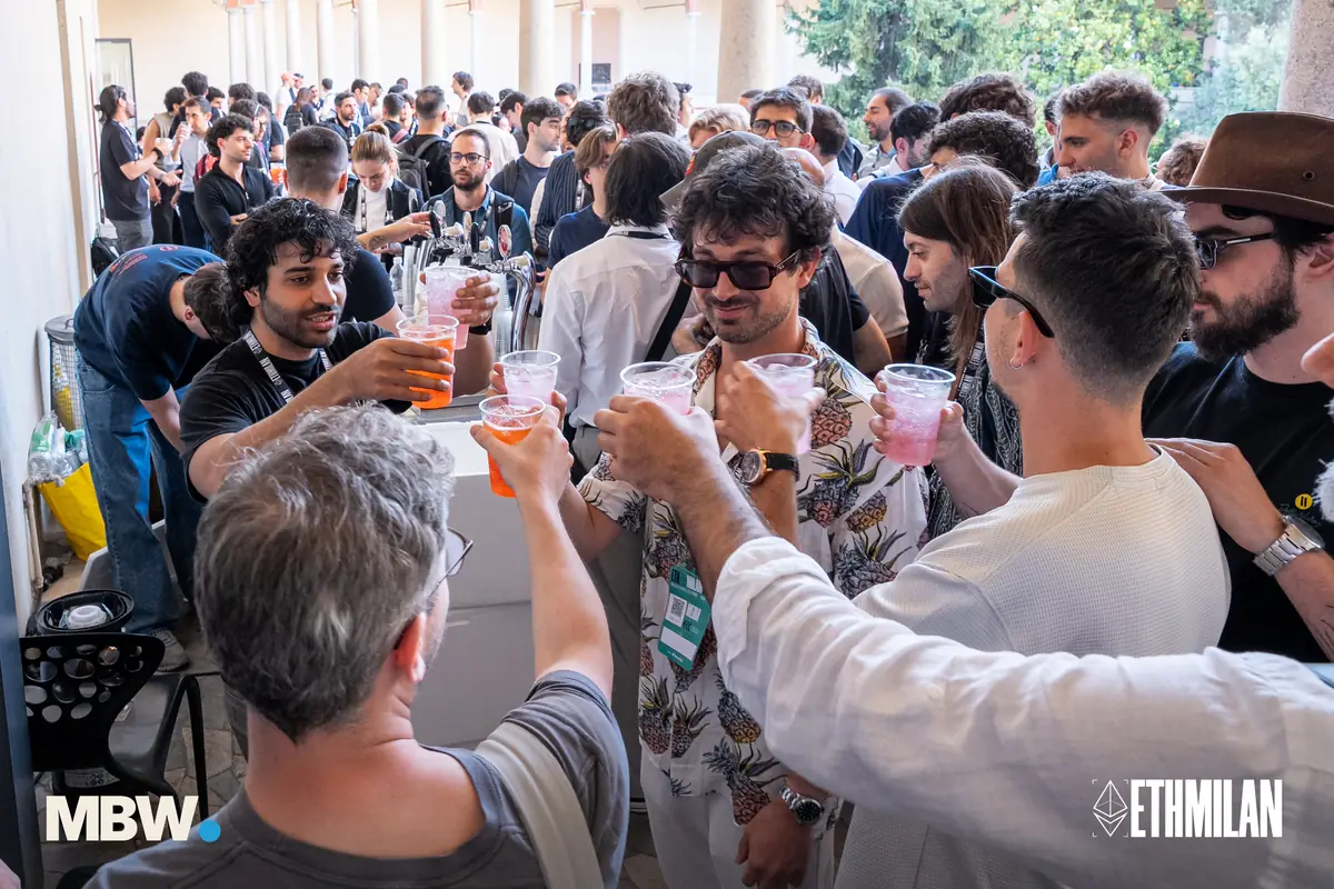 Attendees raising their glasses at the ETHMilan aperitivo, the cloister crowd behind them
